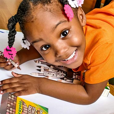 Girl coloring on paper with Colors of the World skin tone Crayola Crayons