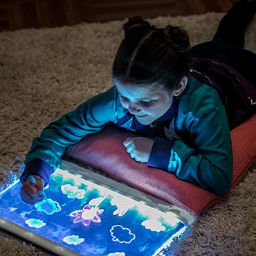 Kid playing with light up board and drawing on designs