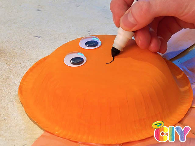 hand drawing smiley face onto octopus with Crayola Marker