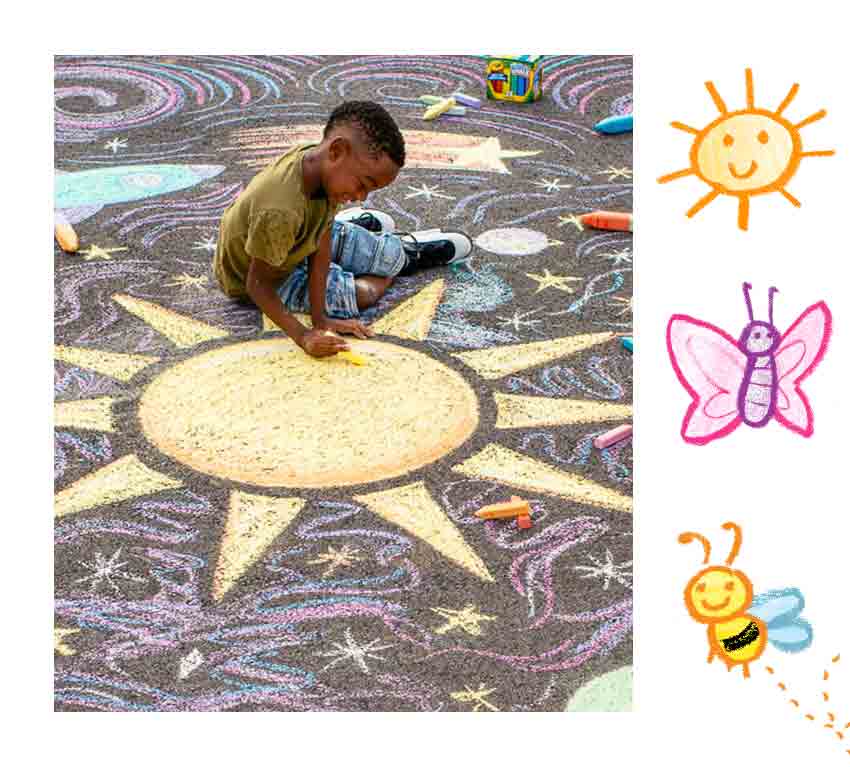 Boy coloring sun, stars, other designs on driveway with Crayola Sidewalk Chalk