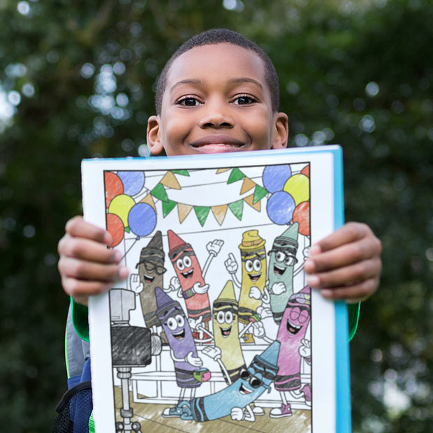 Young boy holding a crayon-colored coloring page of the limited edition characters